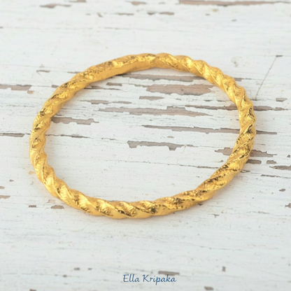 Twisted Viking Hammered 24k 9999 Gold bangle bracelet on white wooden surface, artist's name 'Ella Kripaka' branding