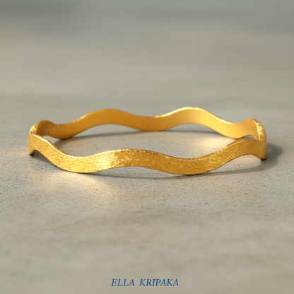 24k gold hammered bracelet bangle with wavy design on grey concrete background, branded 'Ella Kripaka'
