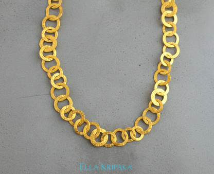 22k gold hammered chain necklace with different links on a grey concrete surface, and with 'Ella Kripaka' branding