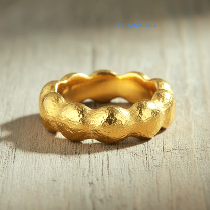 Organic hammered 24k 9999 Gold ring with wavy thick edges on grey old wooden surface, artist-jeweler's name 'Ella Kripaka' is written in picture