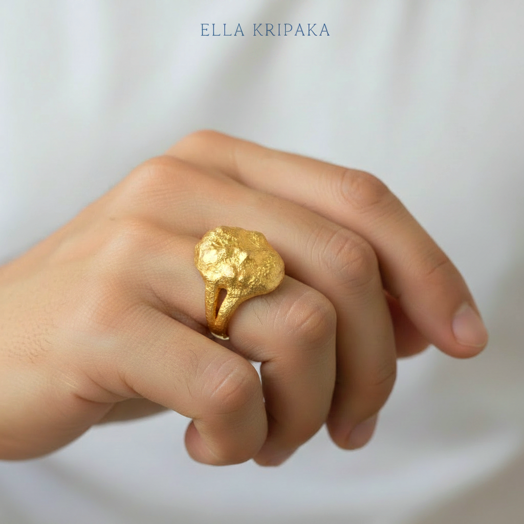 Organic 24k gold convex signet with textured uneven design is worn by a man on finger and on light blurred background, branded 'Ella Kripaka'