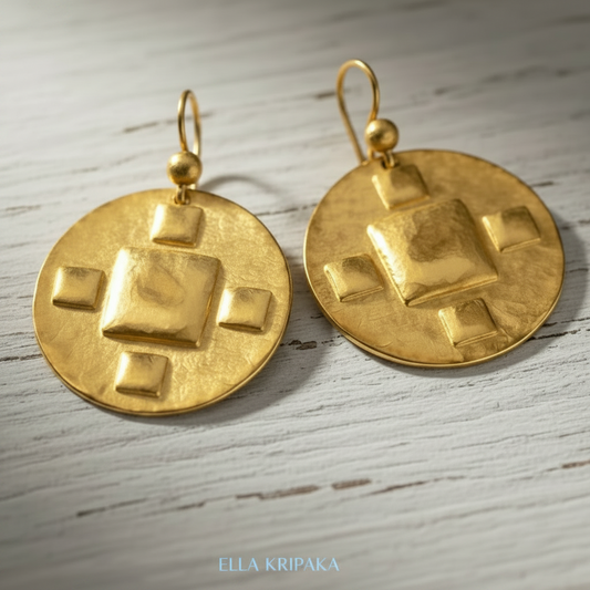 Hammered 24k Gold disk earrings with five convex squares on a light grey old wooden background with 'Ella Kripaka' branding