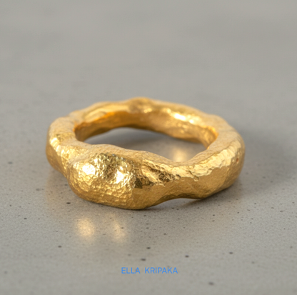 Hammered 24k 9999 Gold thick uneven ring organic with a textured gold surface on a grey concrete background, branded 'Ella Kripaka'