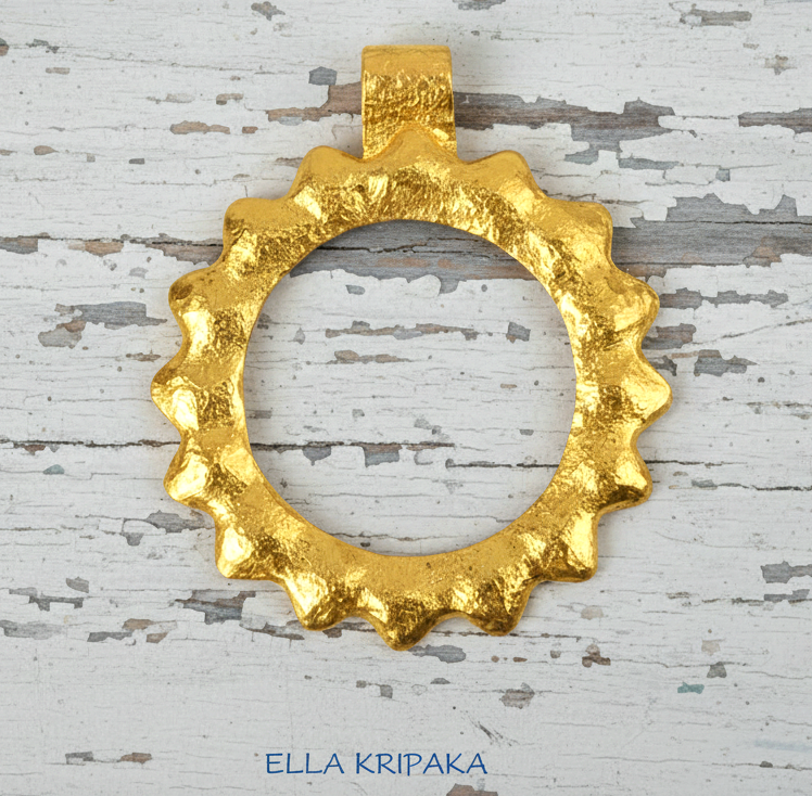 24k 9999 gold hammered convex Sun pendant on a white old wooden surface, branded 'Ella Kripaka'