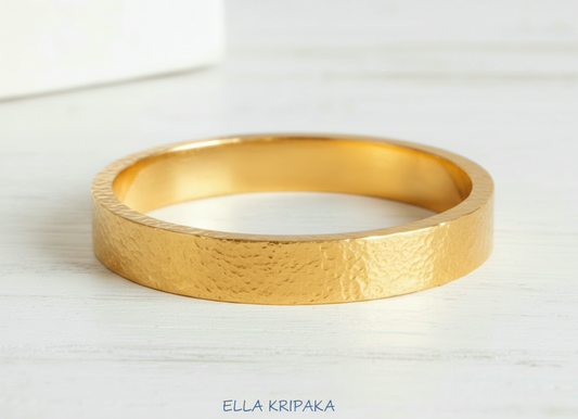 Hammered 24k 9999 Gold thick bangle bracelet Ancient Rome style on white wooden surface, artist's name 'Ella Kripaka' branding