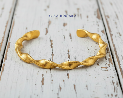 Twisted Viking hammered 24k 9999 gold bracelet cuff on a old white old wooden background, branding artist-jeweler name 'Ella Kripaka'