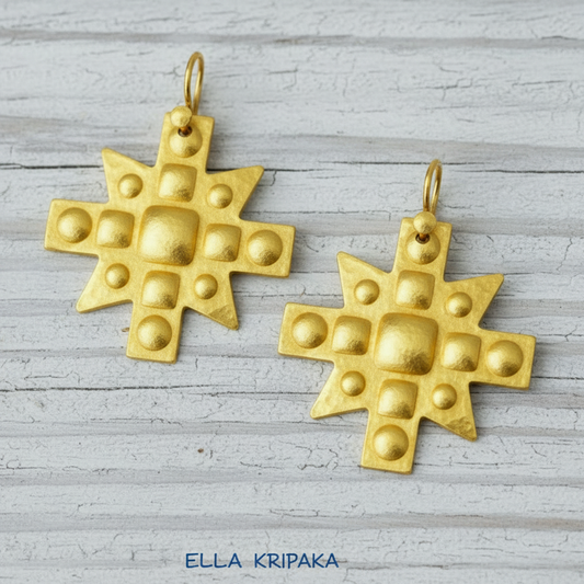 Hammered 24k 9999 Gold Byzantine cross earrings on a old wooden background with 'Ella Kripaka' branding