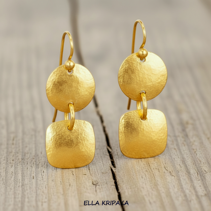 Hammered 24k gold dangling earrings with convex disks and squares are on light rustic wooden background, branding artist-jeweler 'Ella Kripaka'
