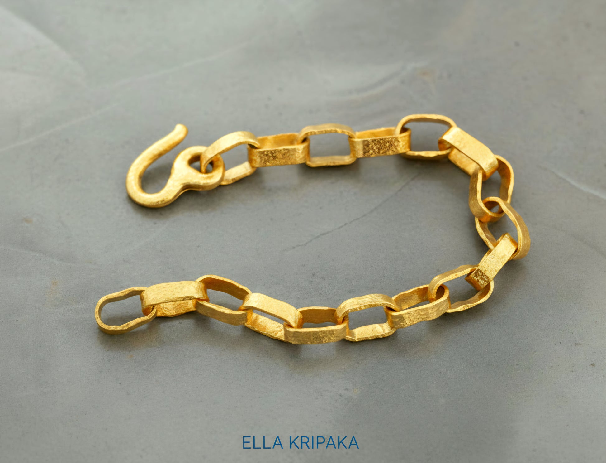 Hammered 24k 9999 gold chain thick bracelet with thick hook clasp Ancient Rome style on a grey background, artist-jeweler name 'Ella Kripaka' branding