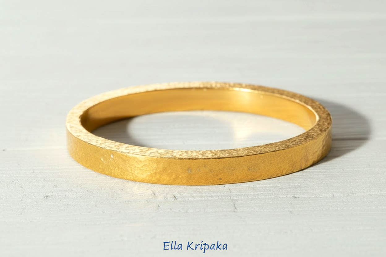 Hammered 24k 9999 gold bangle thick bracelet Ancient Rome style on a white old wooden background, artist-jeweler name 'Ella Kripaka' branding
