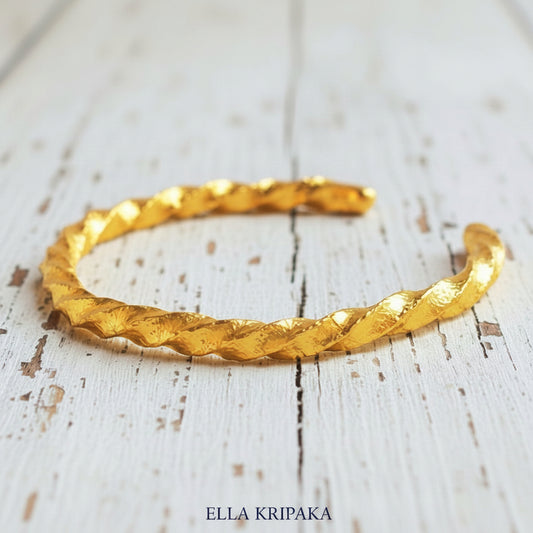 Viking twisted hammered 24k 9999 Gold thick cuff bracelet on a old wooden background, and with 'Ella Kripaka' branding