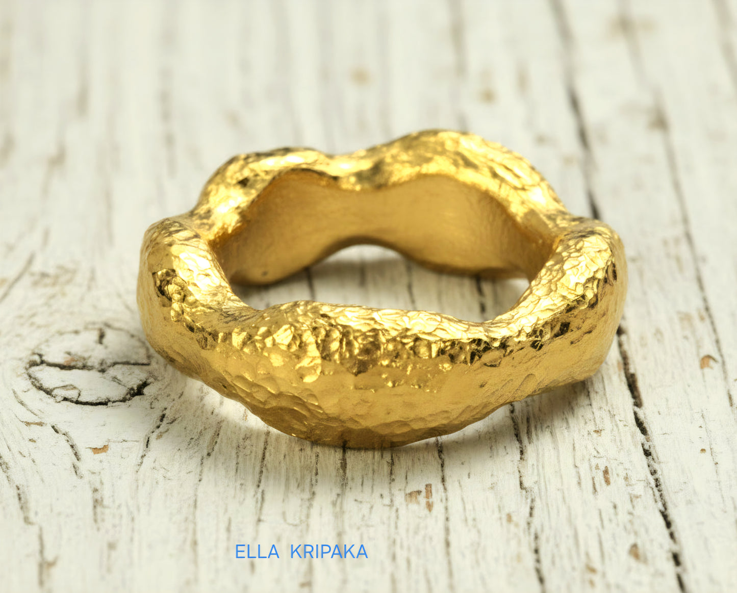 Hammered 24k 9999 Gold thick uneven wavy ring organic with textured gold on a white old wooden background, branded 'Ella Kripaka'