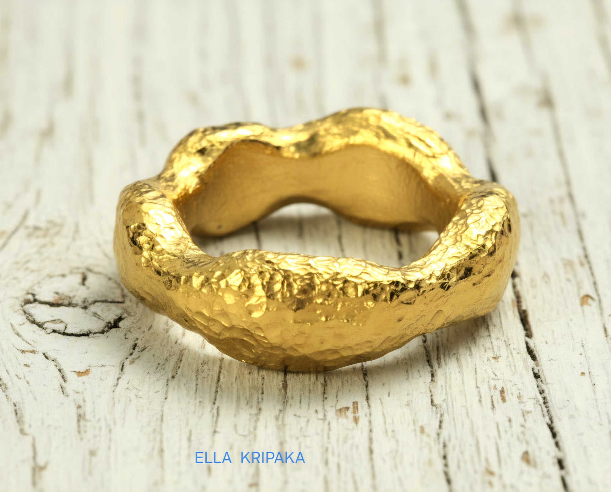 Hammered 24k 9999 Gold thick uneven wavy ring organic with textured gold on a white old wooden background, branded 'Ella Kripaka'