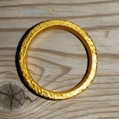 Hammered 24k gold thick ring on rustic wooden surface, artist-jeweler's name 'Ella Kripaka' is branded