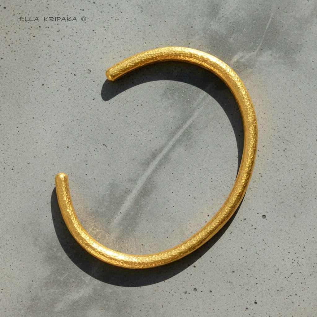 Hammered 24k 9999 gold cuff thick bracelet Ancient Rome style on a grey background, artist-jeweler name 'Ella Kripaka' branding