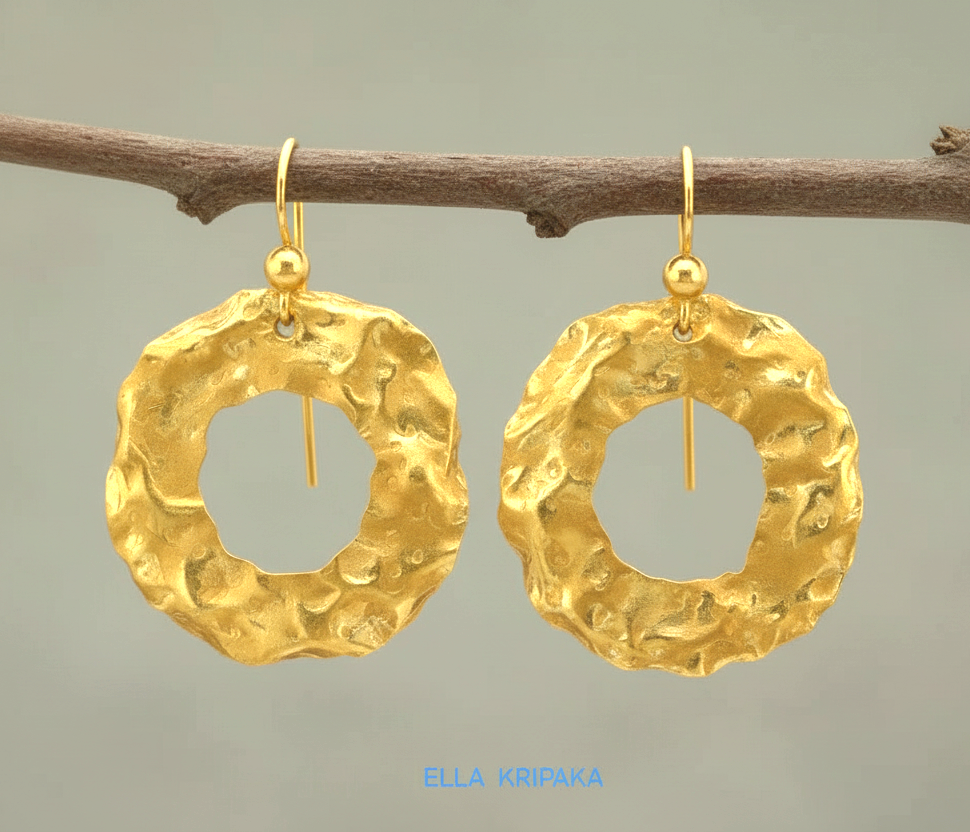 Organic 24k 9999 gold hammered wavy hoops earrings with shiny gold textures are hanging on branch and on grey background, artist-jeweler's name 'Ella Kripaka'