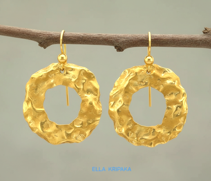 Organic 24k 9999 gold hammered wavy hoops earrings with shiny gold textures are hanging on branch and on grey background, artist-jeweler's name 'Ella Kripaka'