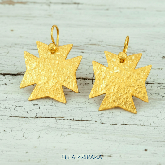 Hammered 24k gold, pure 9999 gold Byzantine cross earrings with shiny forged gold textures on white old wooden surface, artist-jeweler 'Ella Kripaka' branding
