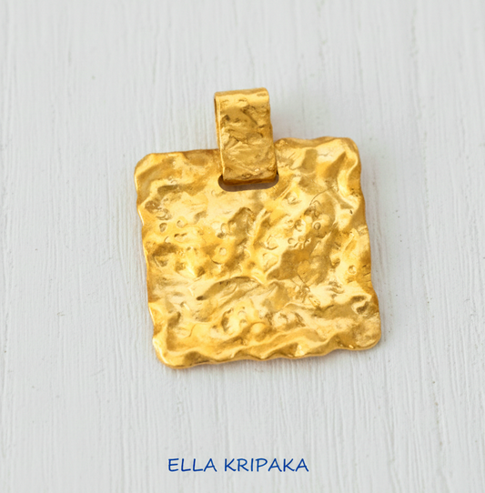Organic 24k gold wavy textured square pendant hammered with uneven edges on white wooden background, with 'Ella Kripaka' branding
