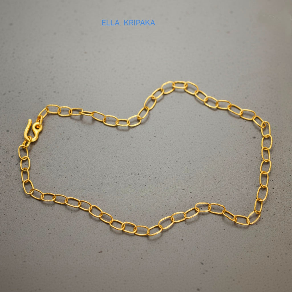 22k gold hammered chain necklace with thick hook clasp on grey concrete background, artist-jeweler's name 'Ella Kripaka' branding