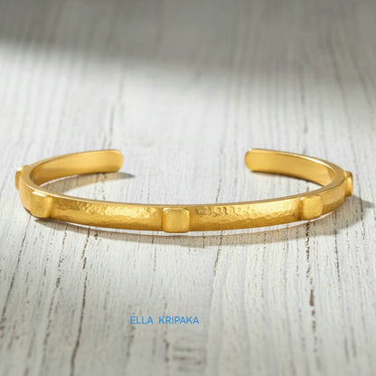 24k gold hammered cuff textured bracelet with thick squares on light rustic wooden surface, artist 'Ella Kripaka' branding