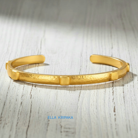 24k gold hammered cuff textured bracelet with thick squares on light rustic wooden surface, artist 'Ella Kripaka' branding