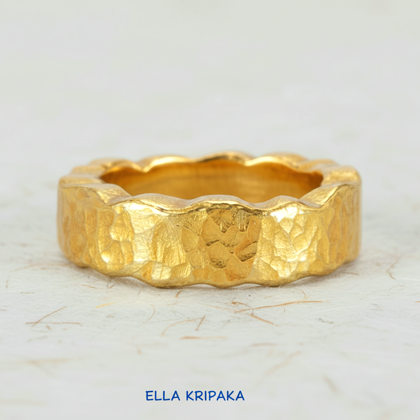 Organic hammered 24k 9999 Gold wavy ring band with thick wavy edges and with forged gold textures on white paper surface, artist-jeweler's name 'Ella Kripaka' branding