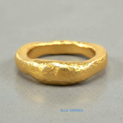 Hammered 24k 9999 Gold thick uneven ring organic signet with a textured gold surface on a grey concrete background, branded 'Ella Kripaka'