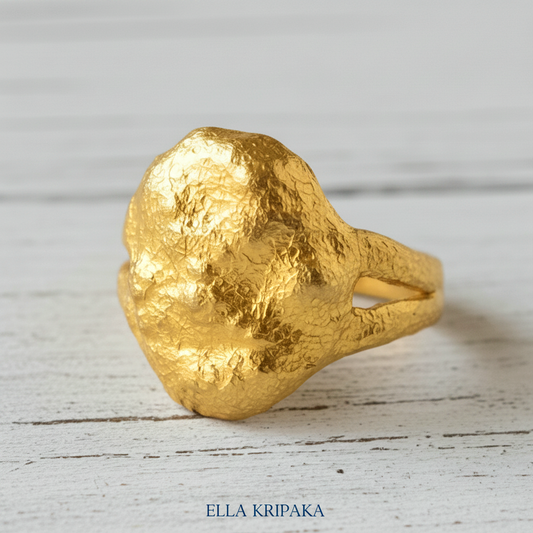 Organic 24k gold ring with textured uneven design on a light rustic wooden surface, branded 'Ella Kripaka'