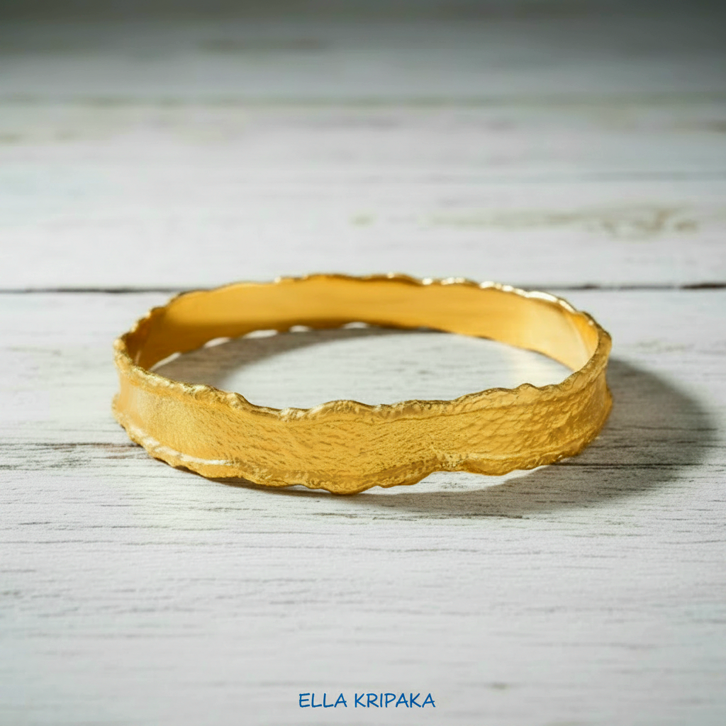 Organic Hammered 24k Gold Bangle Bracelet Textured with uneven thick edges on a white wooden surface, branding artist-jeweler 'Ella Kripaka'