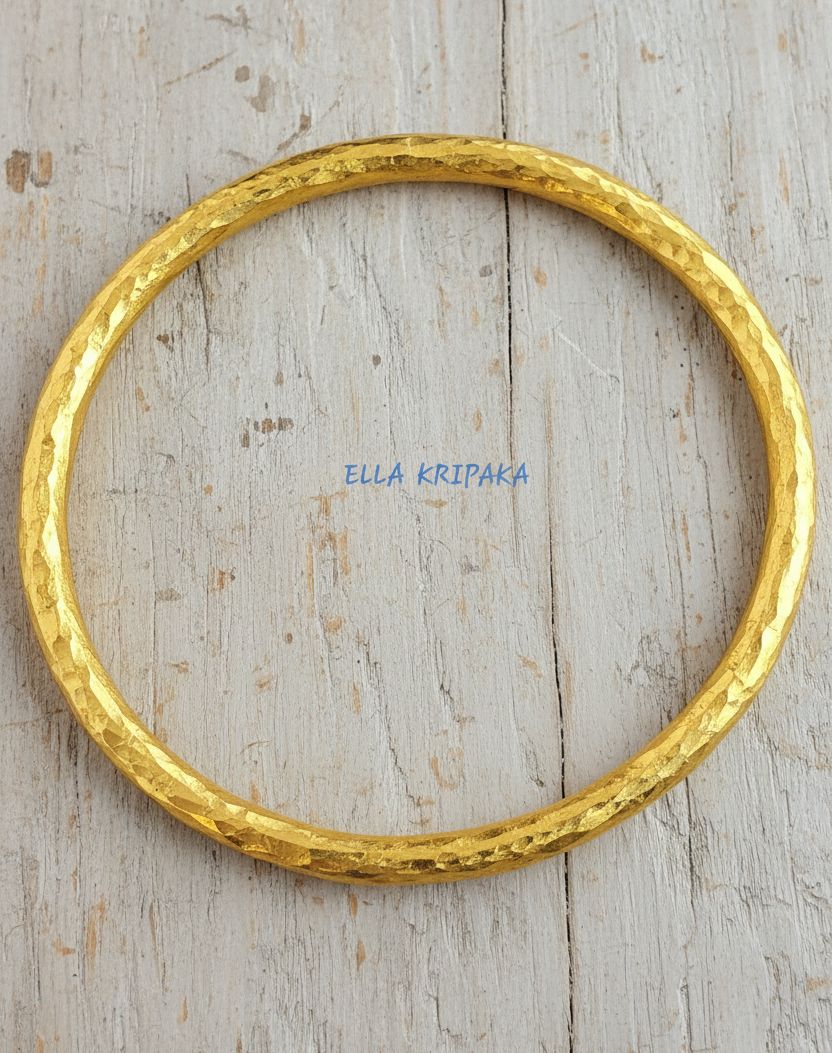 Hammered 24k 9999 gold bangle thick bracelet Ancient Rome style on a wooden background, branding artist-jeweler name 'Ella Kripaka'