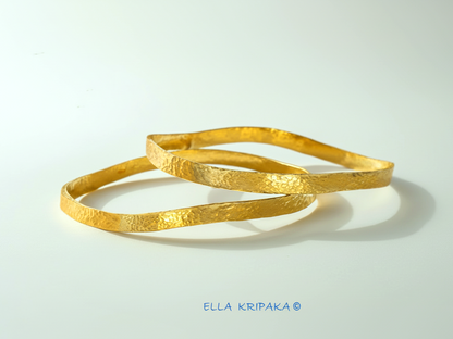 Uneven hammered 24k 9999 Gold organic two bangles bracelets on white surface, artist's name 'Ella Kripaka' branding