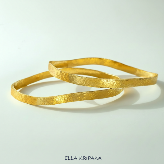 Uneven hammered 24k 9999 Gold organic two bangles bracelets on white surface, artist's name 'Ella Kripaka' branding