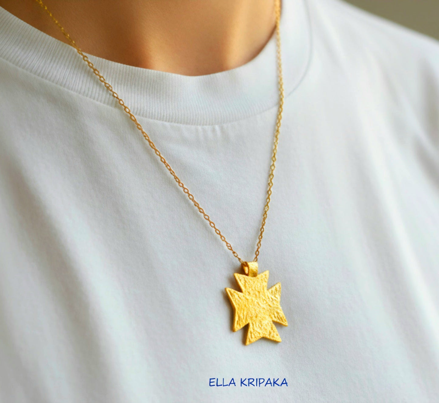 24k gold Byzantine cross pendant textured hammered with chain is worn by a model and with white t-shirt background, with 'Ella Kripaka' branding