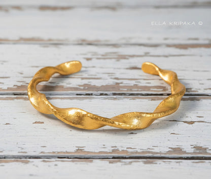 Twisted Viking hammered 24k 9999 gold bracelet cuff on a old white old wooden background, branding artist-jeweler name 'Ella Kripaka'
