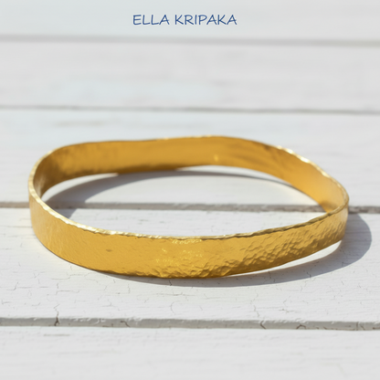 Organic 24k 9999 gold hammered uneven bangle thick bracelet on white wooden surface, artist-jeweler 'Ella Kripaka'
