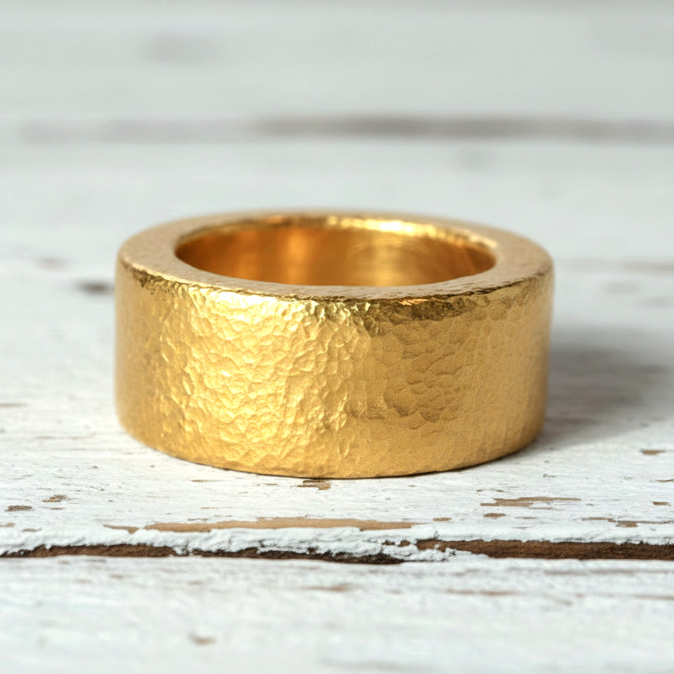 Hammered 24k Gold 9999 gold Ancient Rome  thick ring band with textured gold on a white rustic wooden background, branded 'Ella Kripaka'