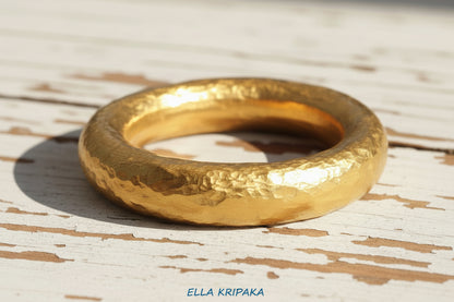 Hammered 24k 9999 Gold ring thick Ancient Rome style on old white wooden surface, artist-jeweler's name 'Ella Kripaka' branding