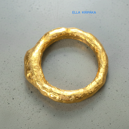 organic hammered 24k Gold thick ring signet with a textured gold surface on a grey concrete background, branded 'Ella Kripaka'