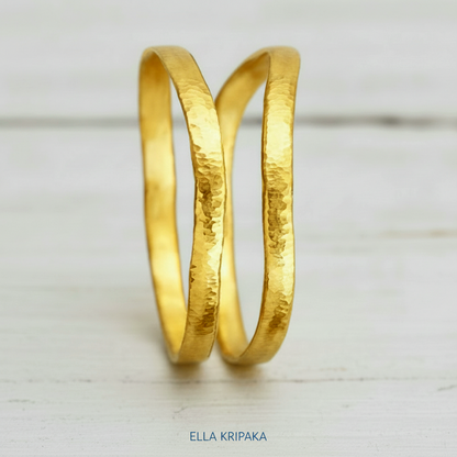 Organic 24k 9999 gold two hammered uneven bangles thick bracelets on white wooden surface, artist-jeweler 'Ella Kripaka'