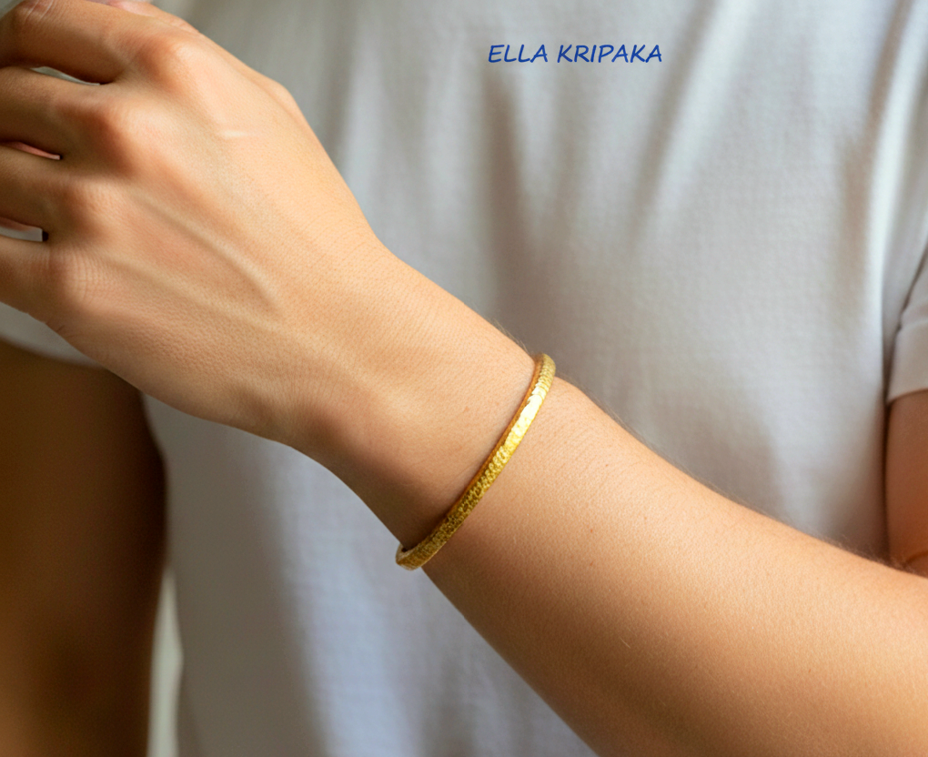 Hammered 24k 9999 gold bangle thick bracelet Ancient Rome style worn by a man on hand and on a white background, artist-jeweler name 'Ella Kripaka'