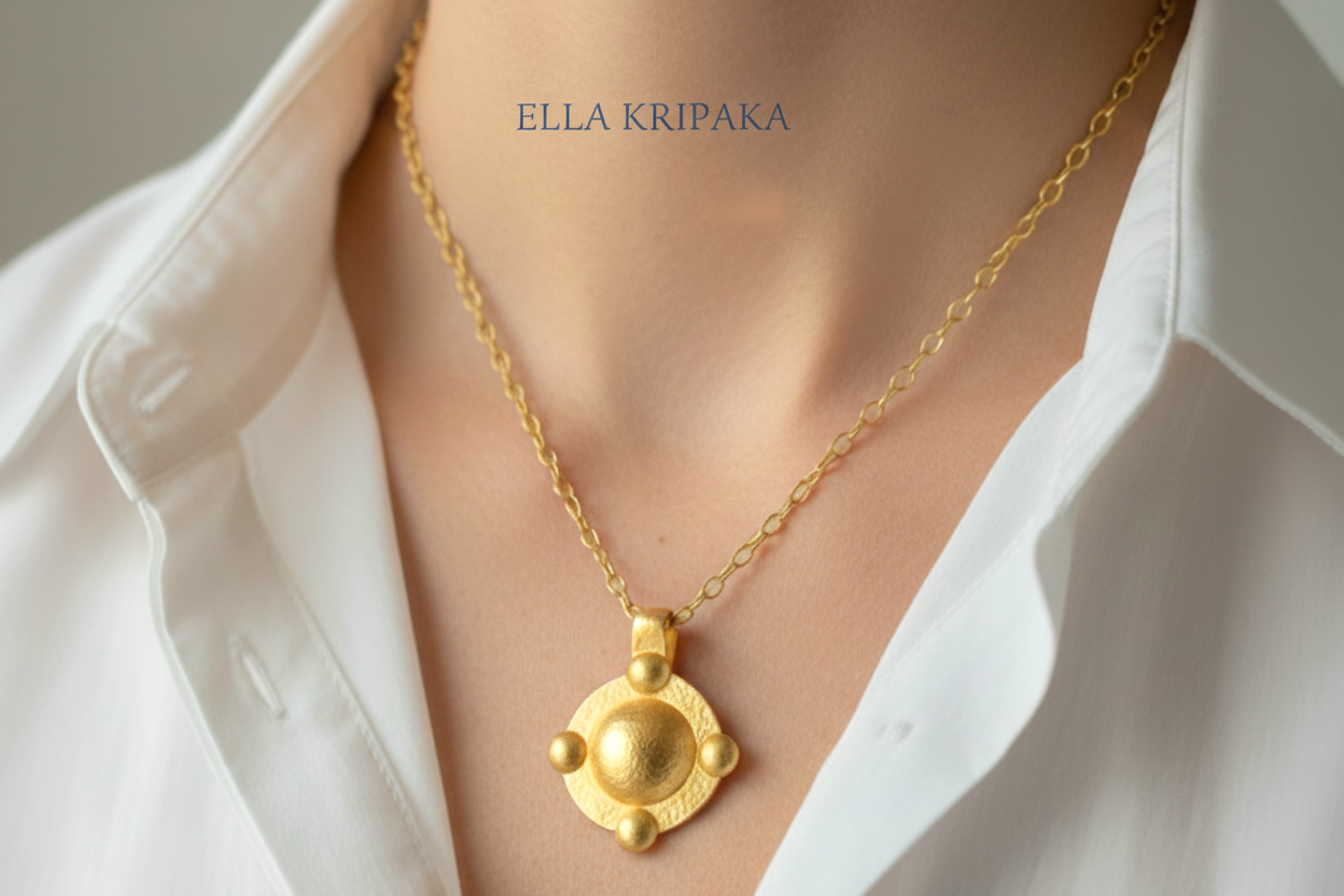 24k gold hammered dome disk with convex rounds textured pendant with chain worn by a woman and with white shirt on grey background, artist 'Ella Kripaka' branding