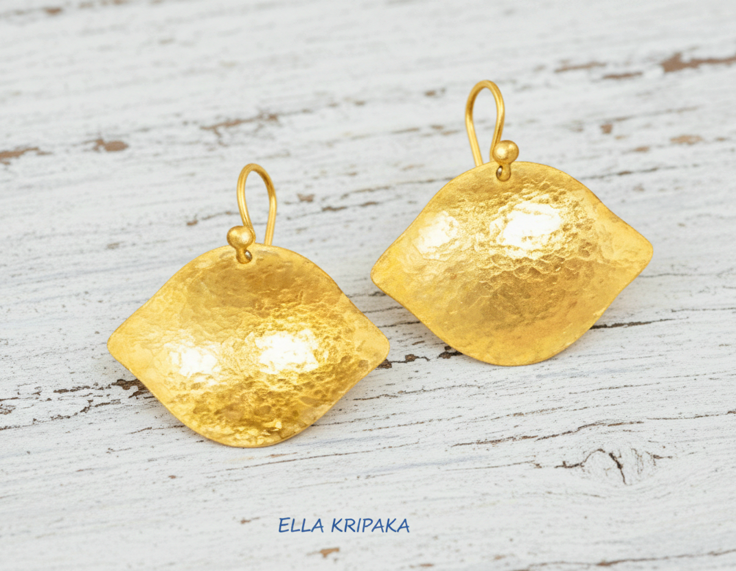 Hammered 24k 9999 Gold Byzantine convex earrings on a old white wooden background with 'Ella Kripaka' branding