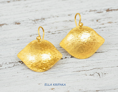 Hammered 24k 9999 Gold Byzantine convex earrings on a old white wooden background with 'Ella Kripaka' branding