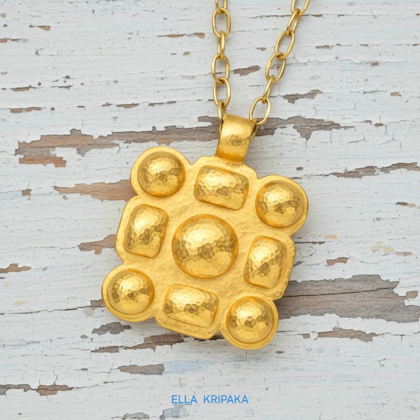 Hammered 24k gold square pendant with convex pattern and with chain on a white rustic wooden surface with 'Ella Kripaka' branding