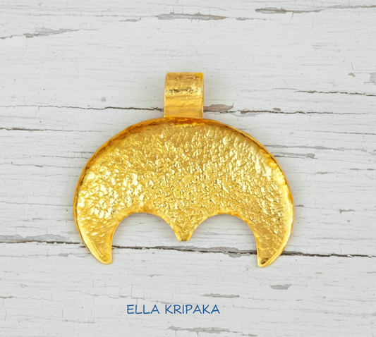 Hammered 24k gold convex Moon pendant on a white rustic wooden background with 'Ella Kripaka' branding