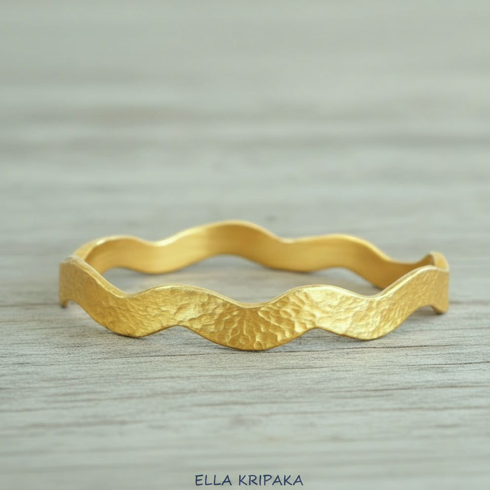 Hammered 24k 9999 Gold wavy bangle bracelet Ancient Egypt style on white wooden surface, artist's name 'Ella Kripaka' branding