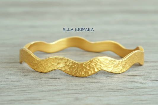 Hammered 24k 9999 Gold wavy bangle bracelet Ancient Egypt style on white wooden surface, artist's name 'Ella Kripaka' branding
