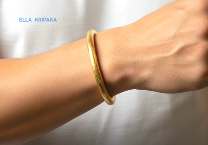 24k 9999 gold hammered Ancient Rome thick cuff bracelet worn on a wtist by a man and on a blurred background, branded 'Ella Kripaka'