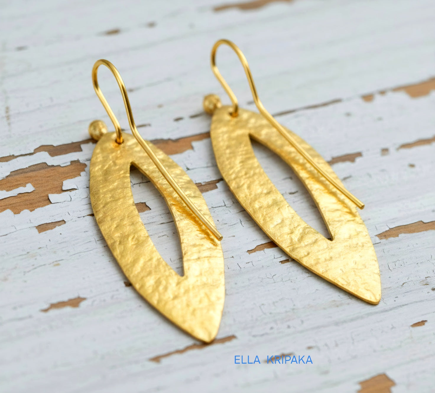 Hammered 24k 9999 Gold Byzantine leaf earrings on a old white wooden background with 'Ella Kripaka' branding
